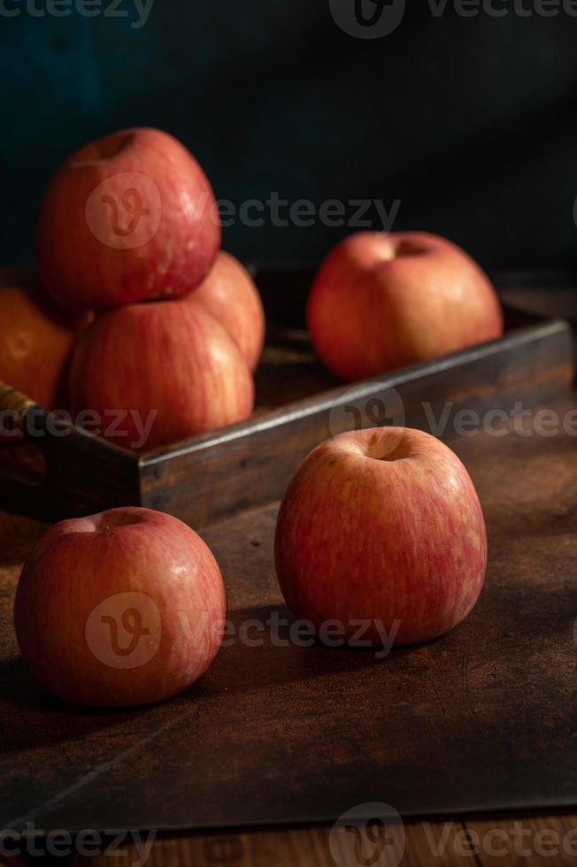 las manzanas en el plato parecen pinturas al óleo bajo la luz tenue de la mesa de madera foto