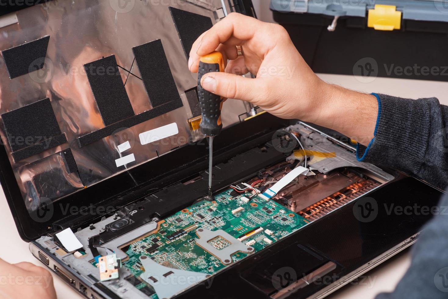 Wizard repairs laptop with tools and hands photo