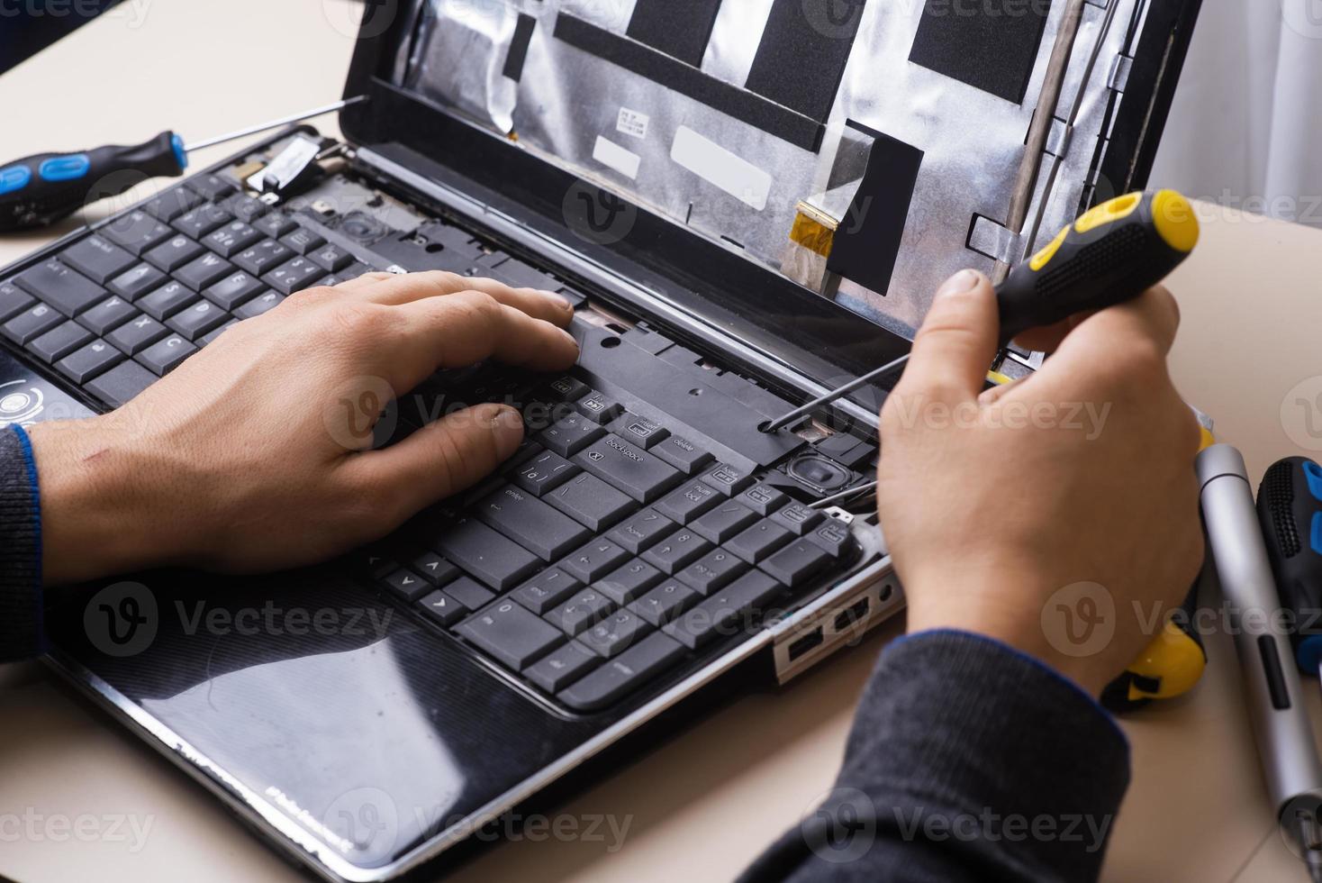 Wizard repairs laptop with tools and hands photo