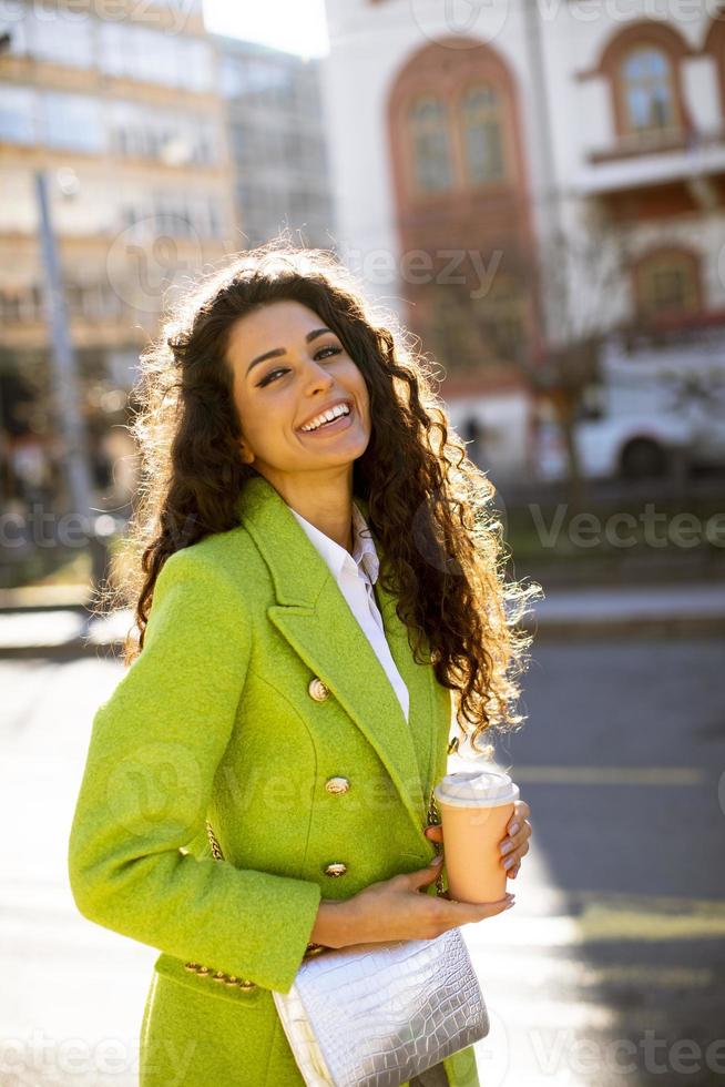 mujer joven sosteniendo café para llevar en la calle foto