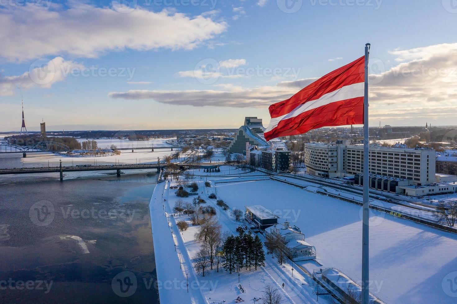 vista panorámica de la ciudad de riga con una gran bandera letona junto al río daugava. espíritu letón. foto