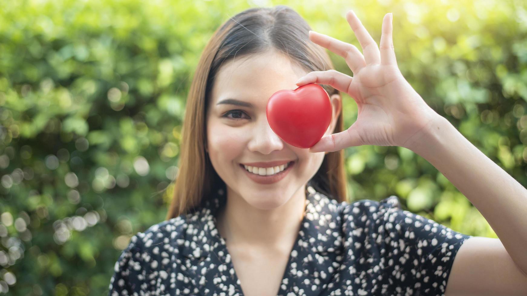 la mano de la mujer sostiene el corazón rojo, el amor y el concepto de atención médica foto