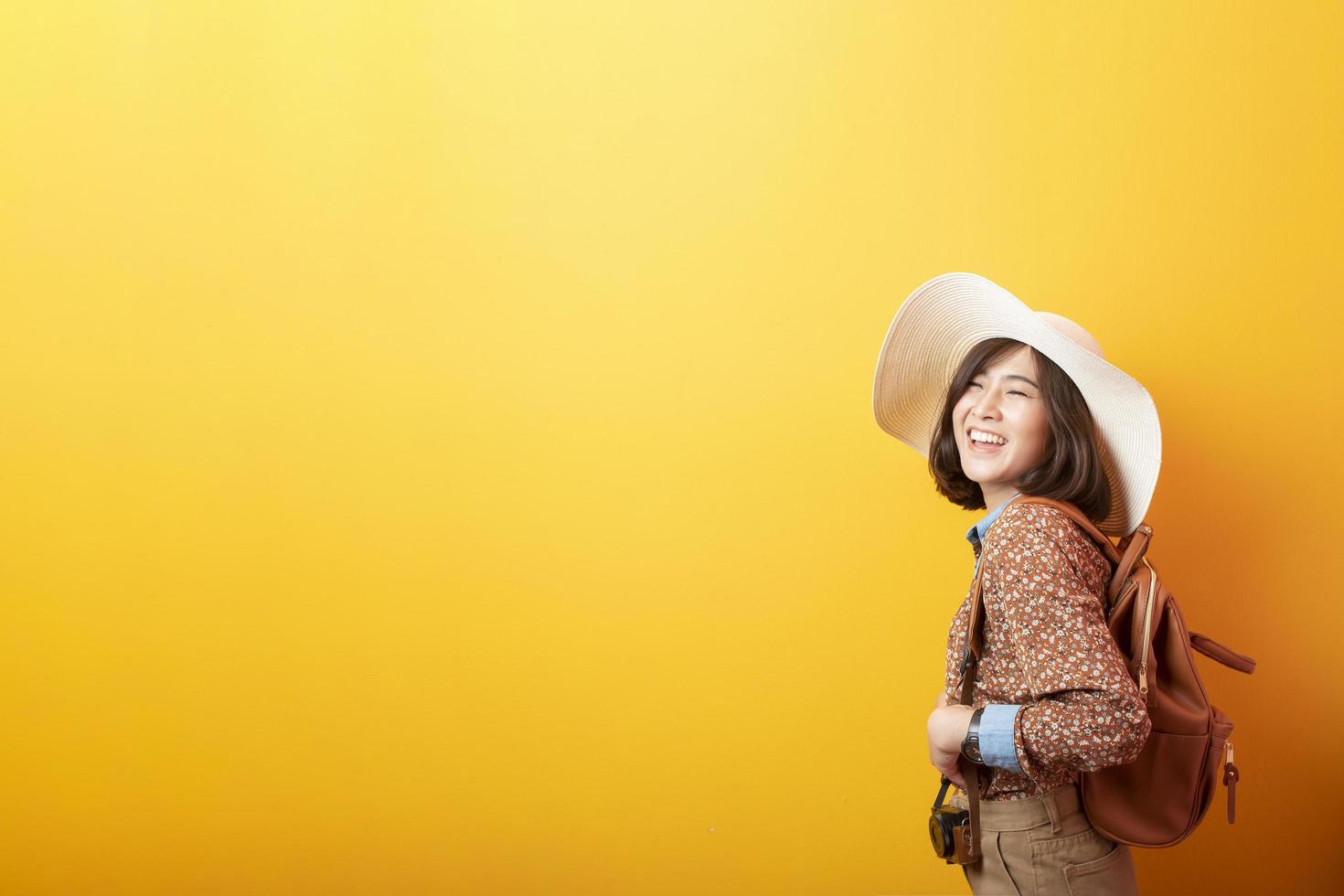 feliz joven turista asiática sobre fondo amarillo foto