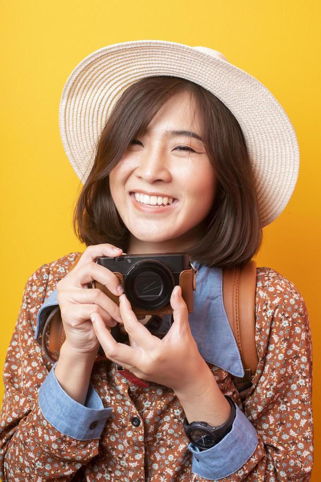 Happy Young Asian tourist woman on yellow background photo