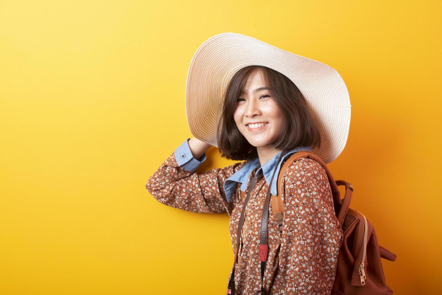 Happy Young Asian tourist woman on yellow background photo