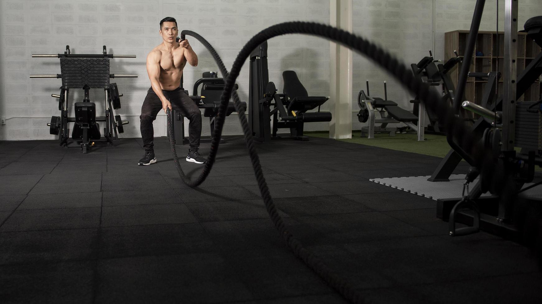 Asian athletic man with  rope doing exercise in fitness gym photo