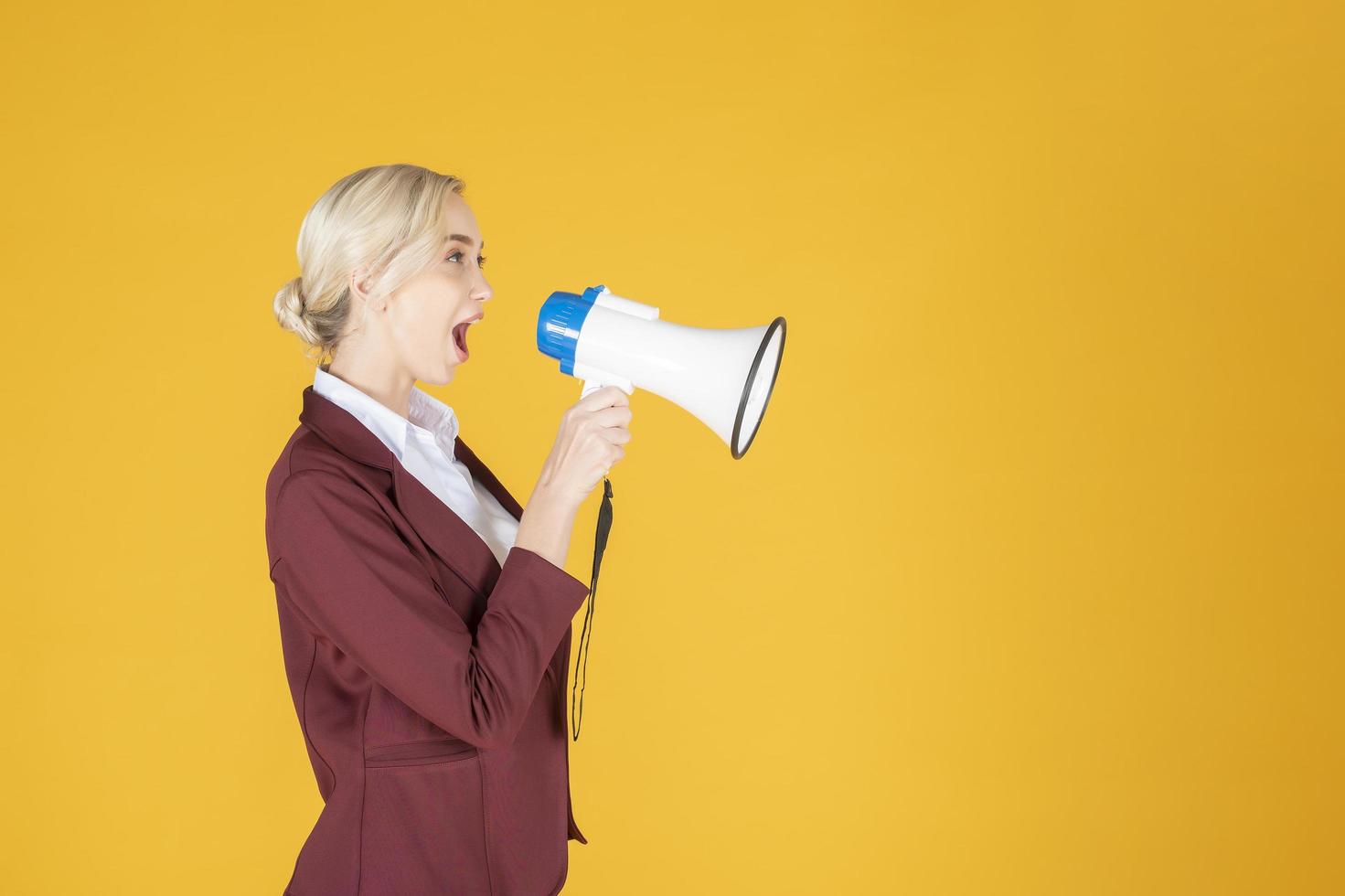 Business woman is announcing from megaphone on yellow background photo