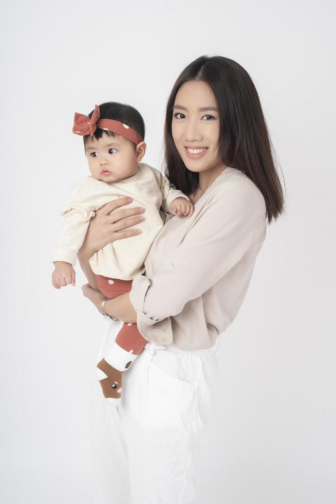 la madre asiática y la adorable niña son felices con antecedentes blancos foto