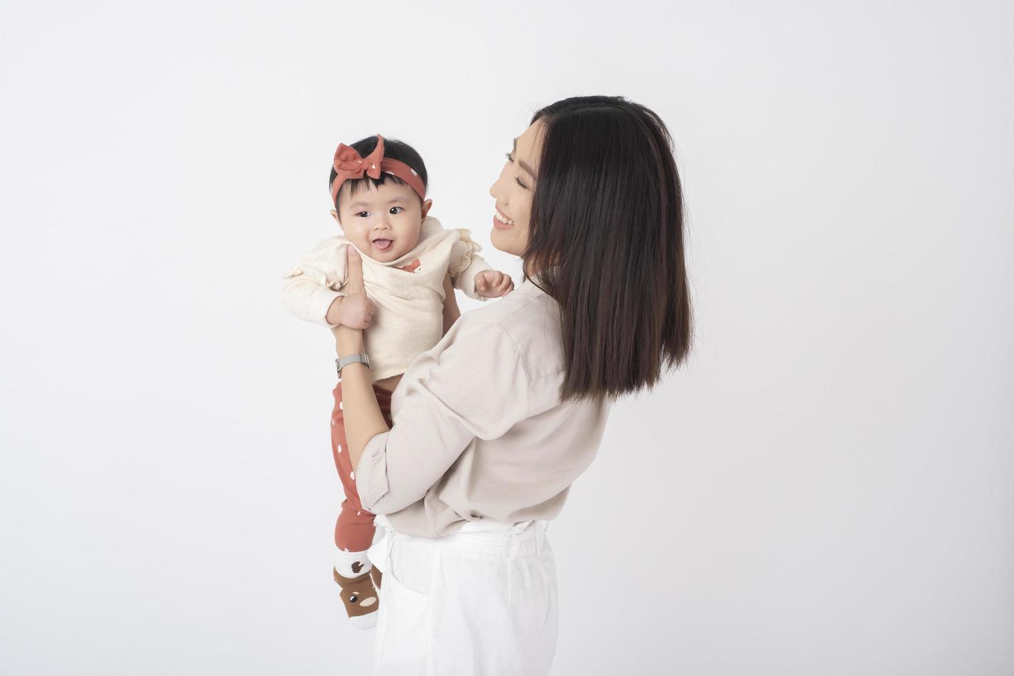 la madre asiática y la adorable niña son felices con antecedentes blancos foto