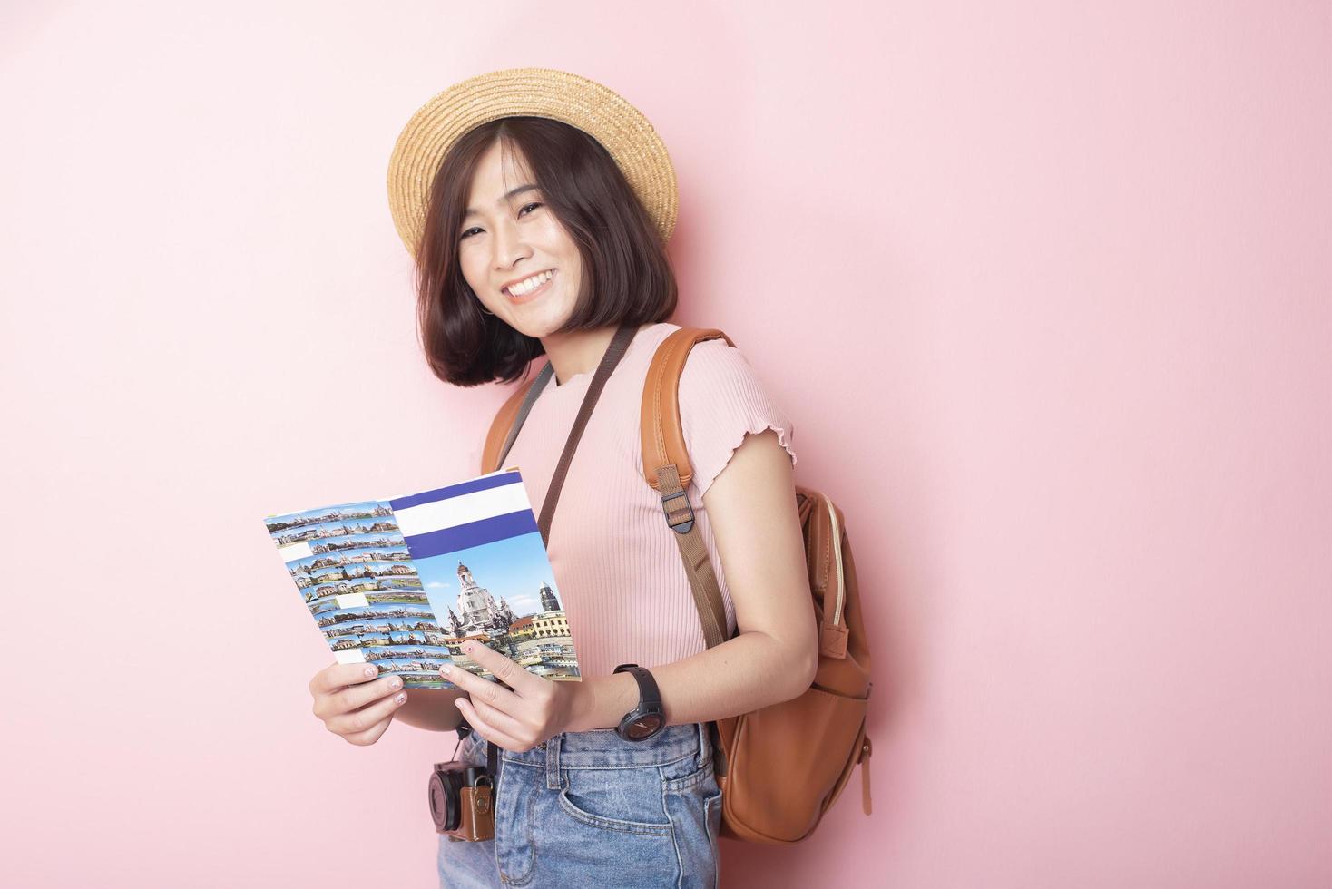 Happy Asian woman tourist  on pink background photo