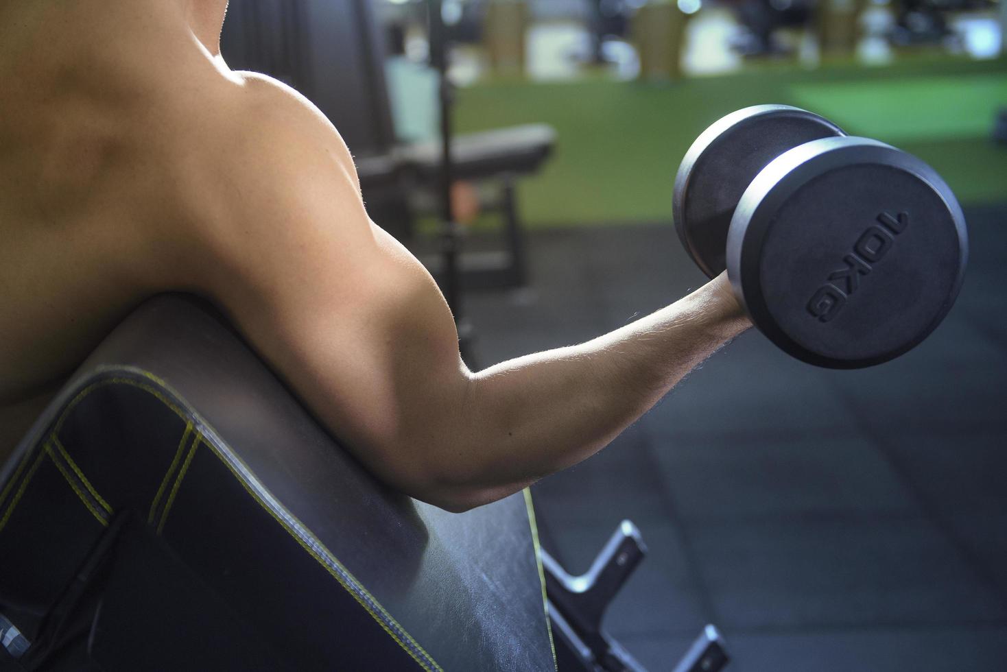 Muscular fitness man bodybuilder is workout with dumbbells in gym photo