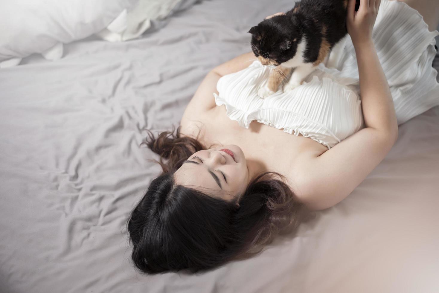 hermosa mujer asiática amante de los gatos está jugando con un gato en su habitación foto