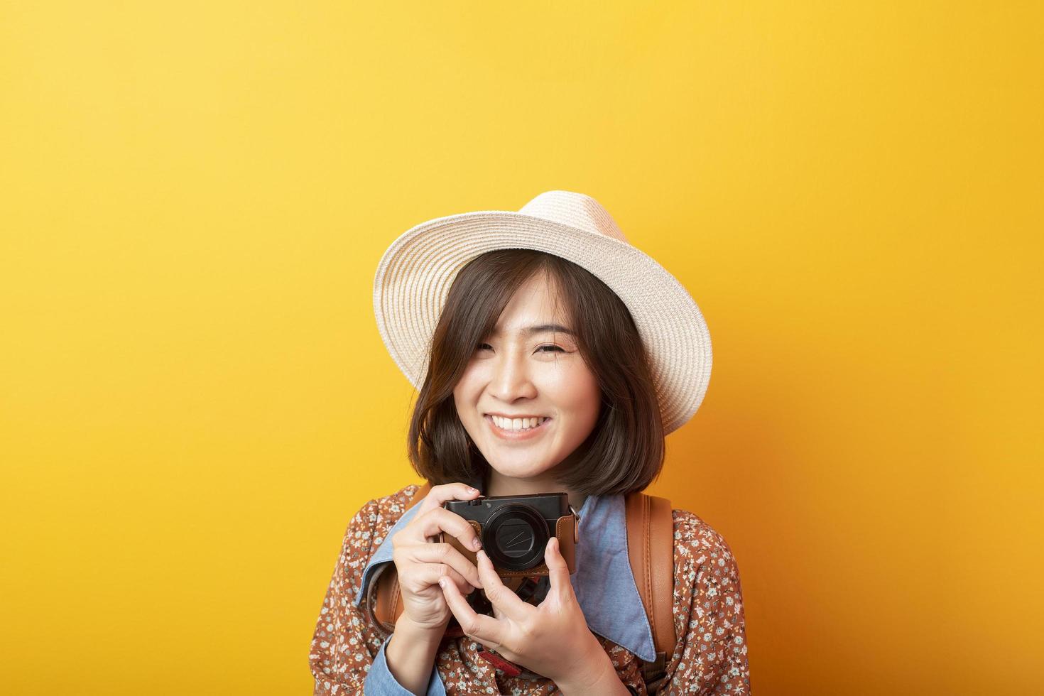 Happy Young Asian tourist woman on yellow background photo