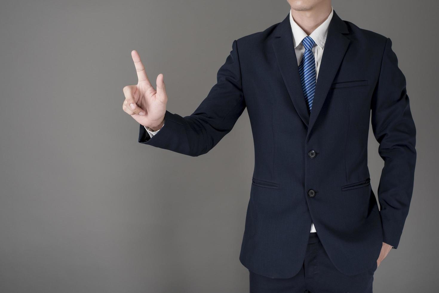 Business man is touching on virtual screen , grey background in studio photo