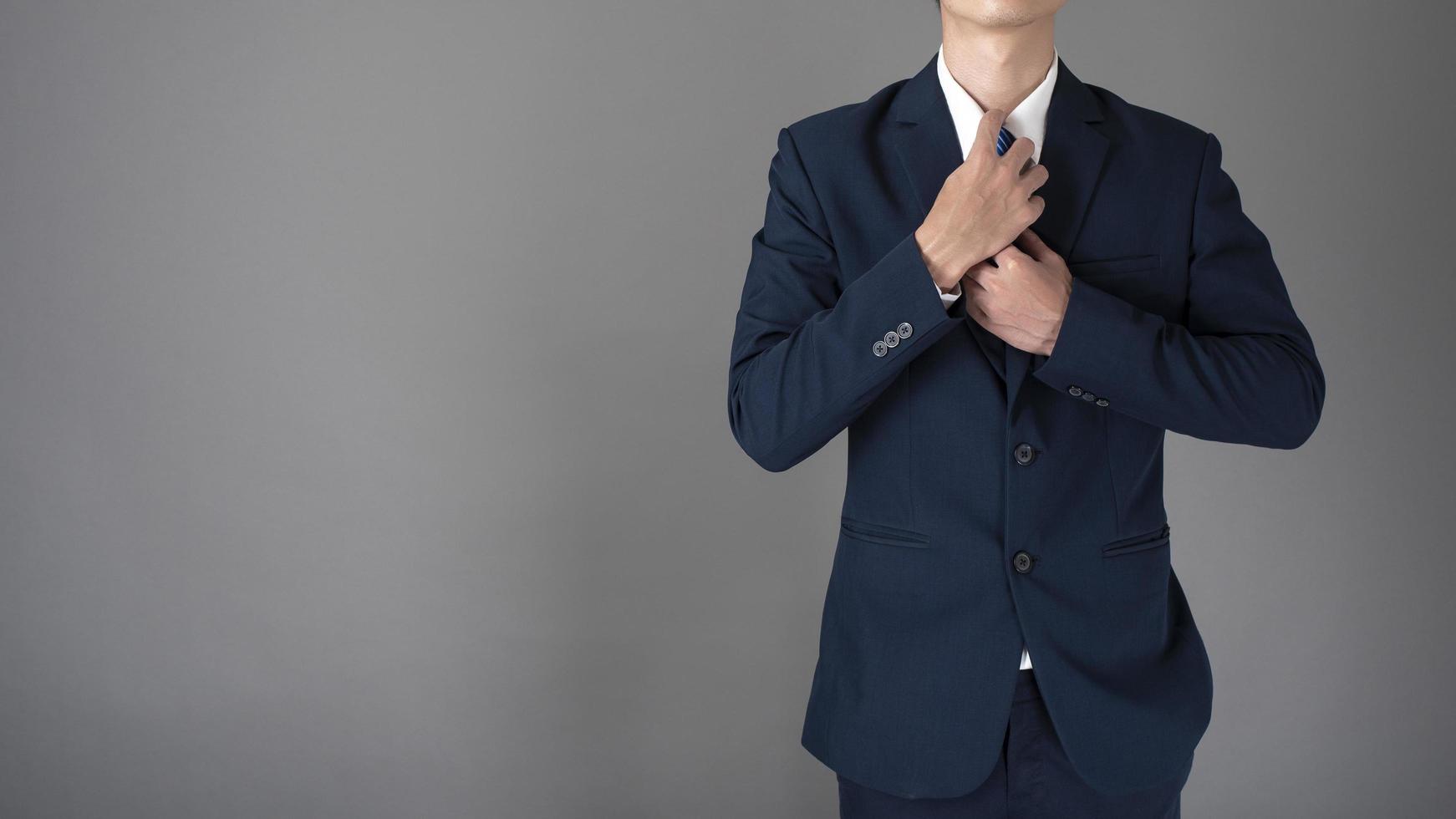 Cerca del hombre de negocios en traje azul confía en fondo gris foto