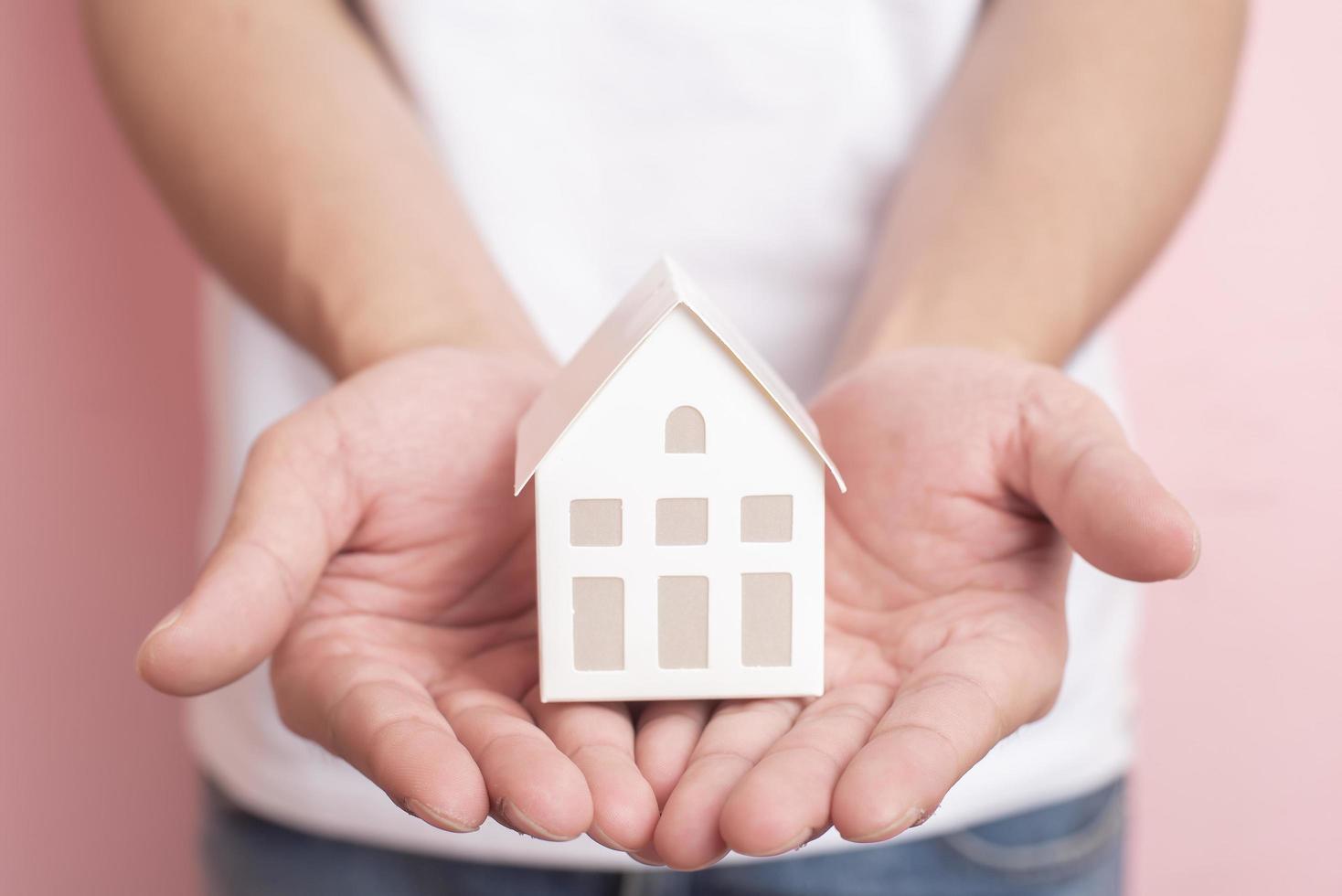 Small white house on human hand photo