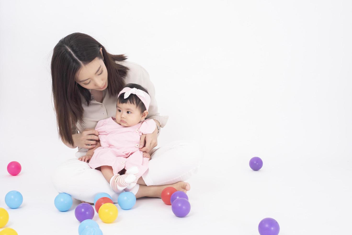 la madre asiática y la adorable niña son felices con antecedentes blancos foto