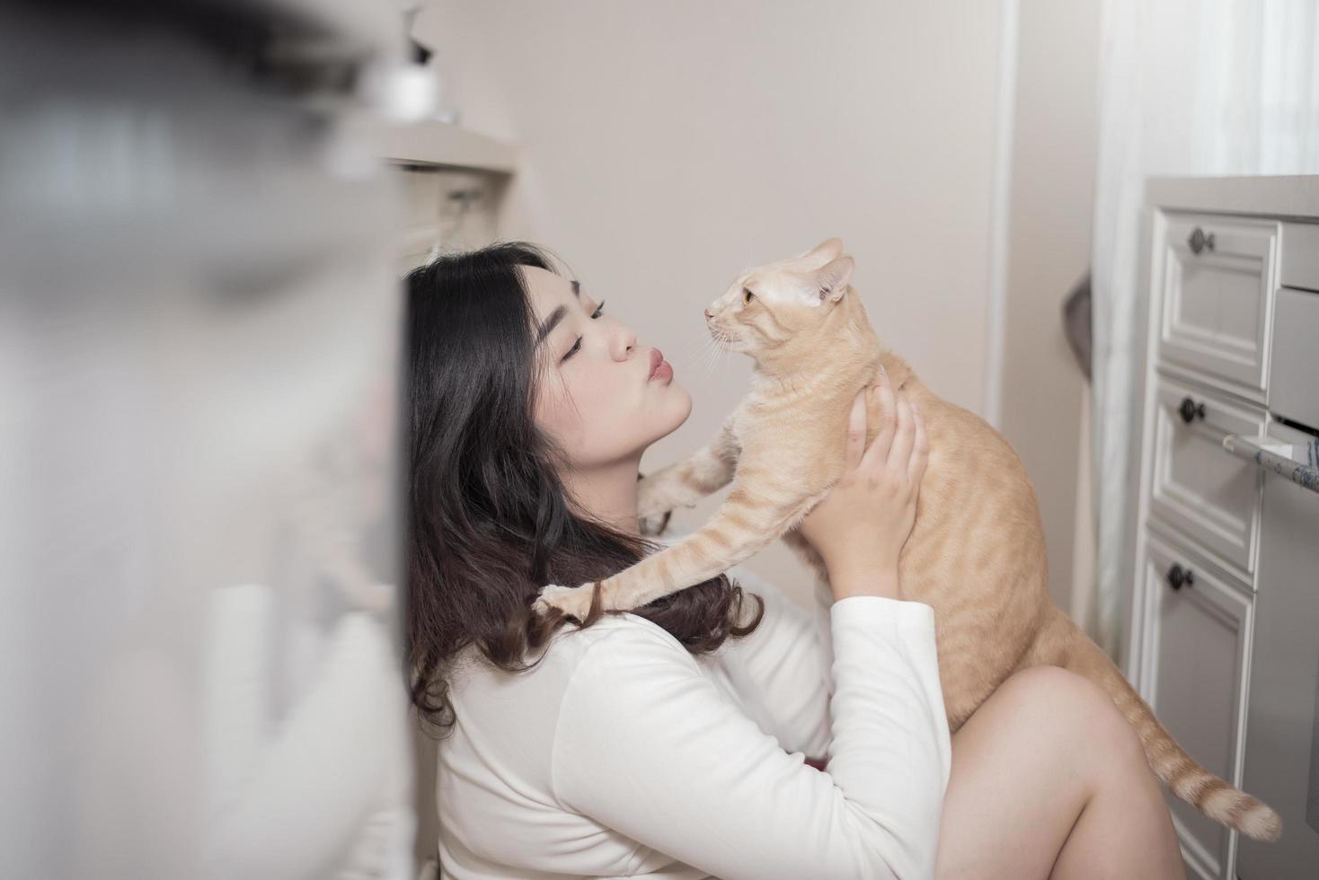 hermosa mujer asiática amante de los gatos está jugando con un gato en su habitación foto