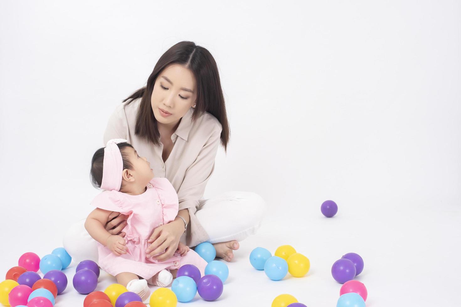 la madre asiática y la adorable niña son felices con antecedentes blancos foto