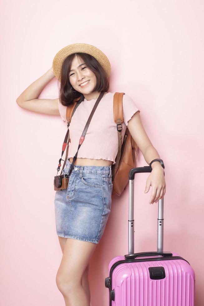 mujer asiática feliz turista sobre fondo rosa foto