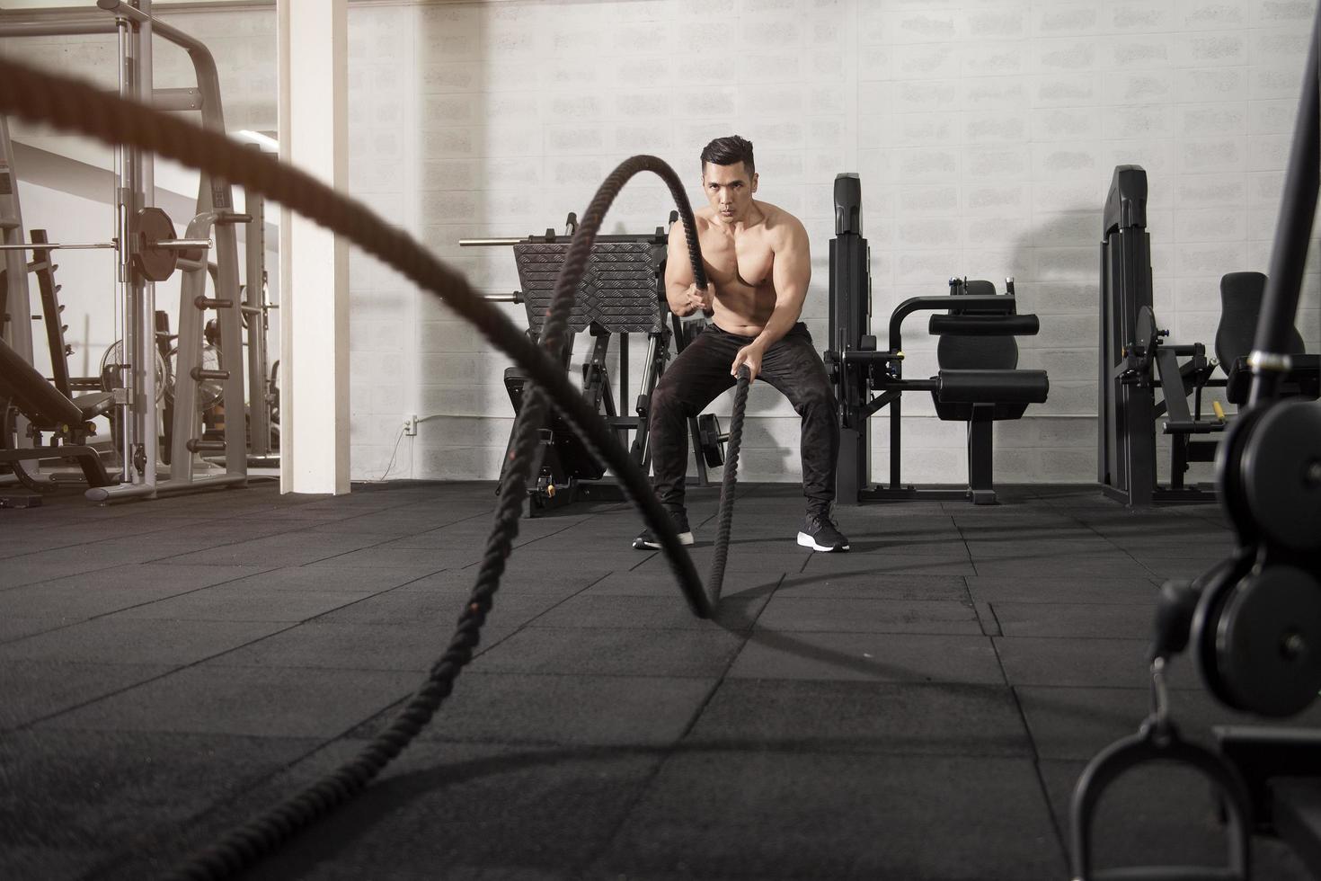 Asian athletic man with  rope doing exercise in fitness gym photo