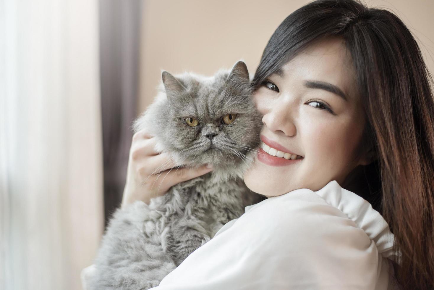 hermosa mujer asiática amante de los gatos está jugando con un gato en su habitación foto