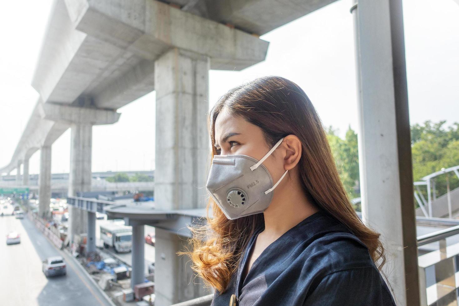 hermosa mujer con máscara antipolvo protege la contaminación del aire y pm 2.5 en la ciudad de la calle foto