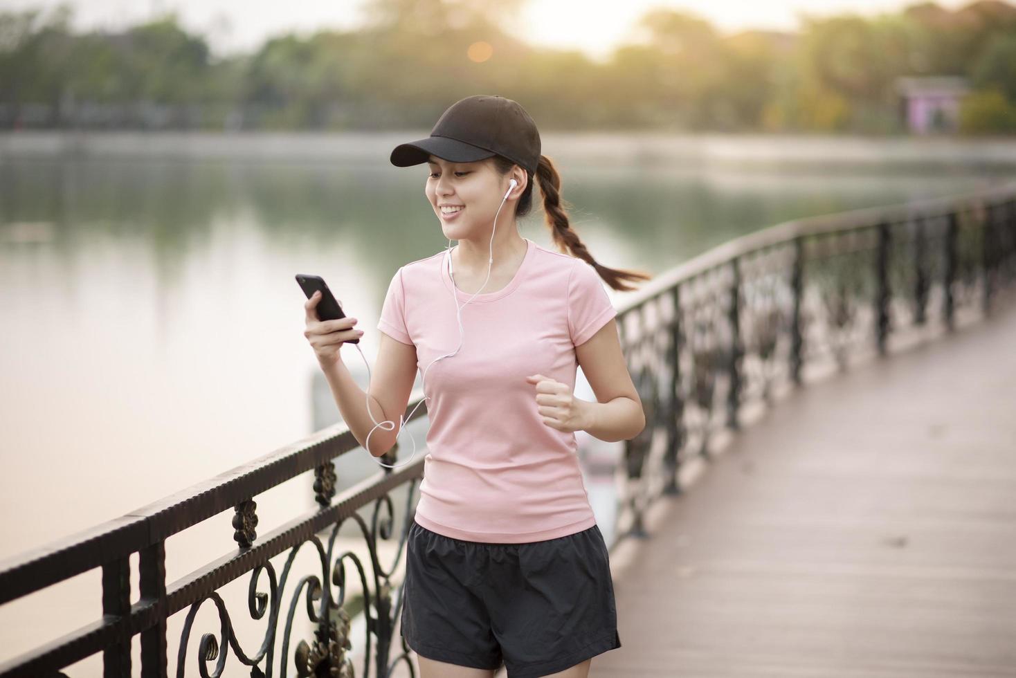 Beautiful woman is listening music and jogging  in the park photo