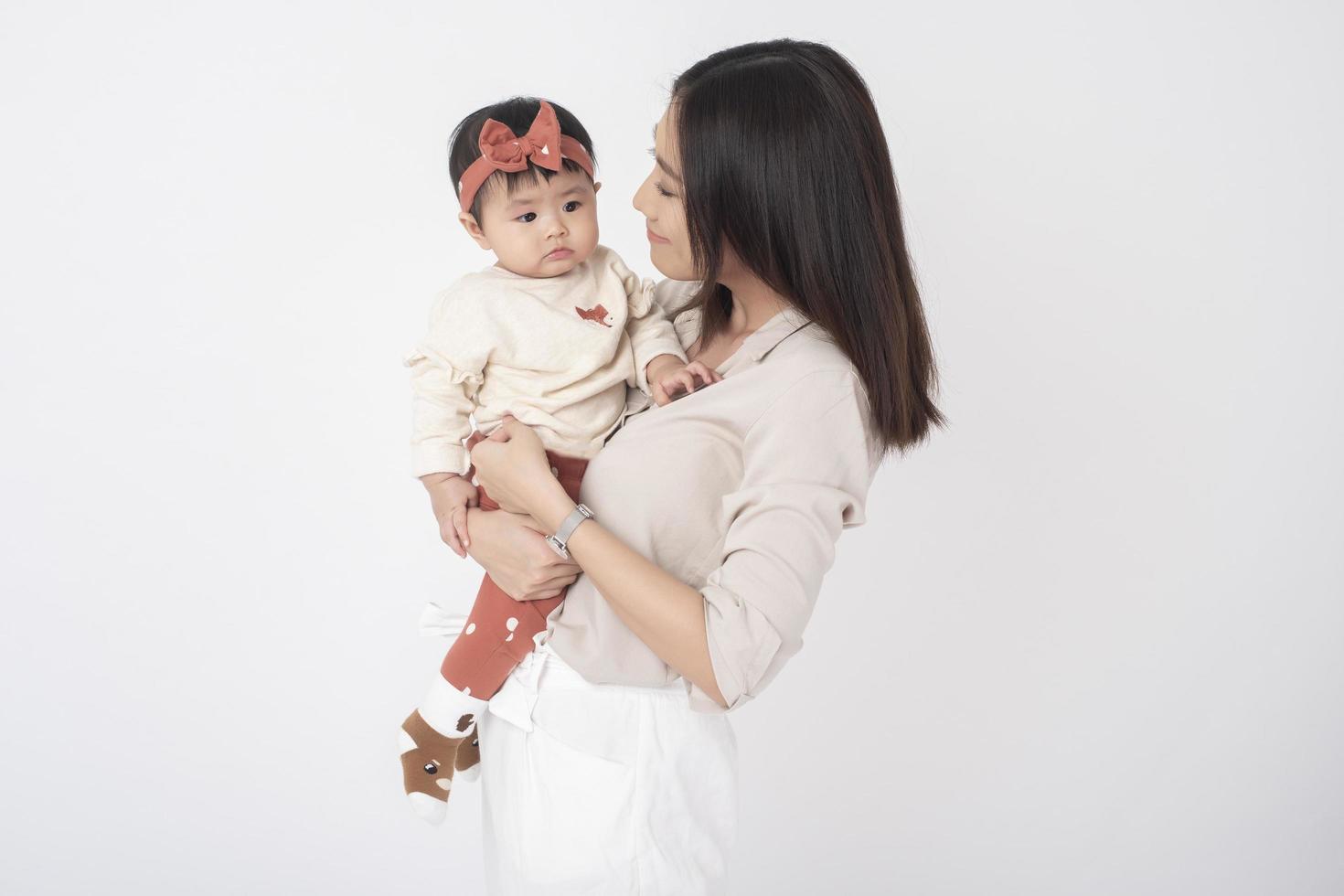 la madre asiática y la adorable niña son felices con antecedentes blancos foto