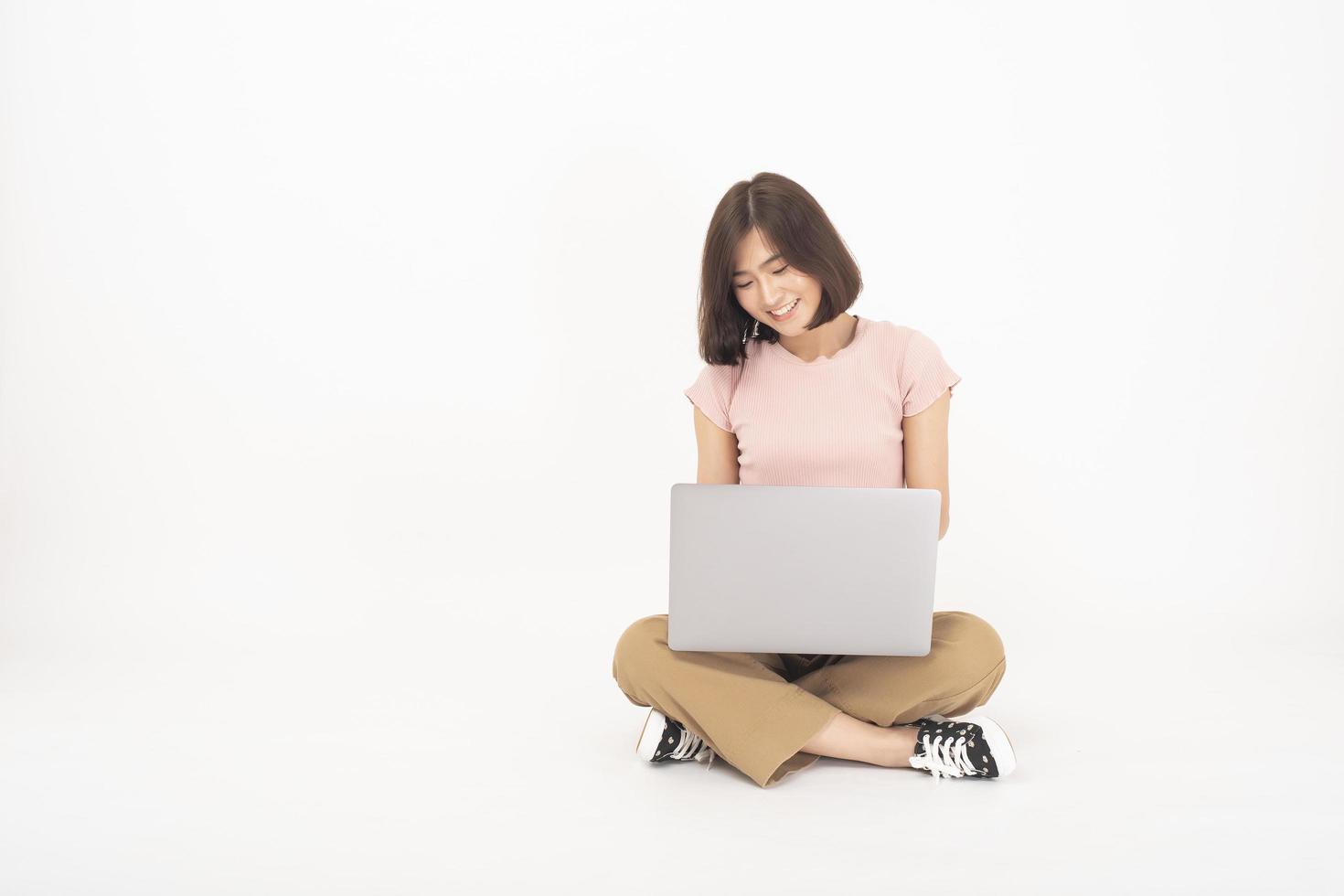 Una linda adolescente asiática está trabajando con una computadora de fondo blanco foto