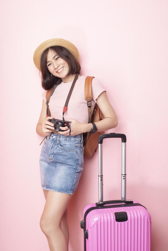 Happy Asian woman tourist  on pink background photo