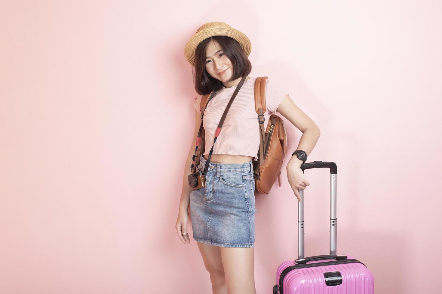 Happy Asian woman tourist  on pink background photo