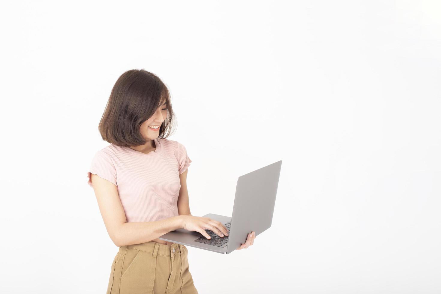 Una linda adolescente asiática está trabajando con una computadora de fondo blanco foto