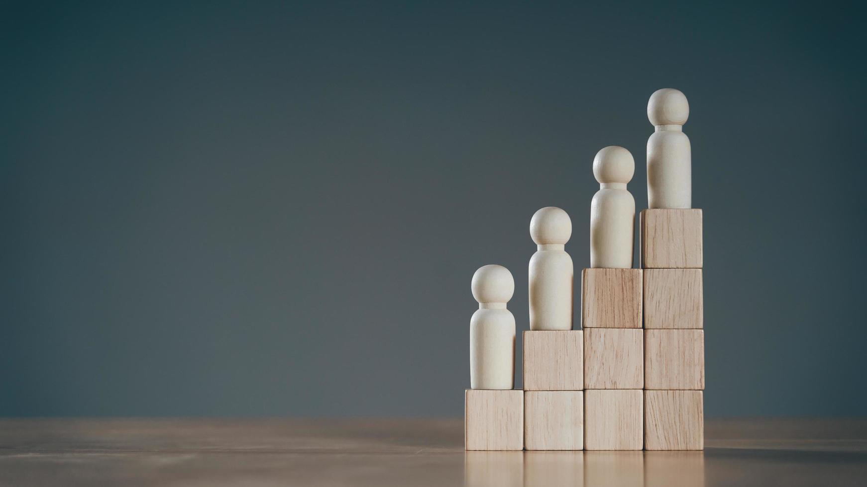 Wooden peg dolls on Stack of wooden blocks. Employees positions. Human resource management planning. photo