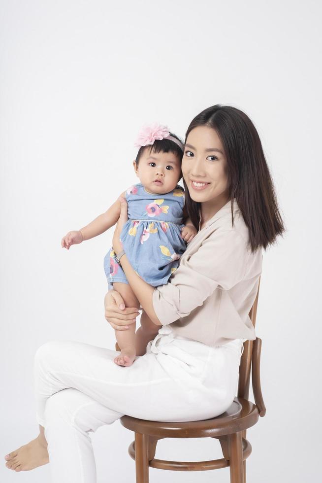 la madre asiática y la adorable niña son felices con antecedentes blancos foto