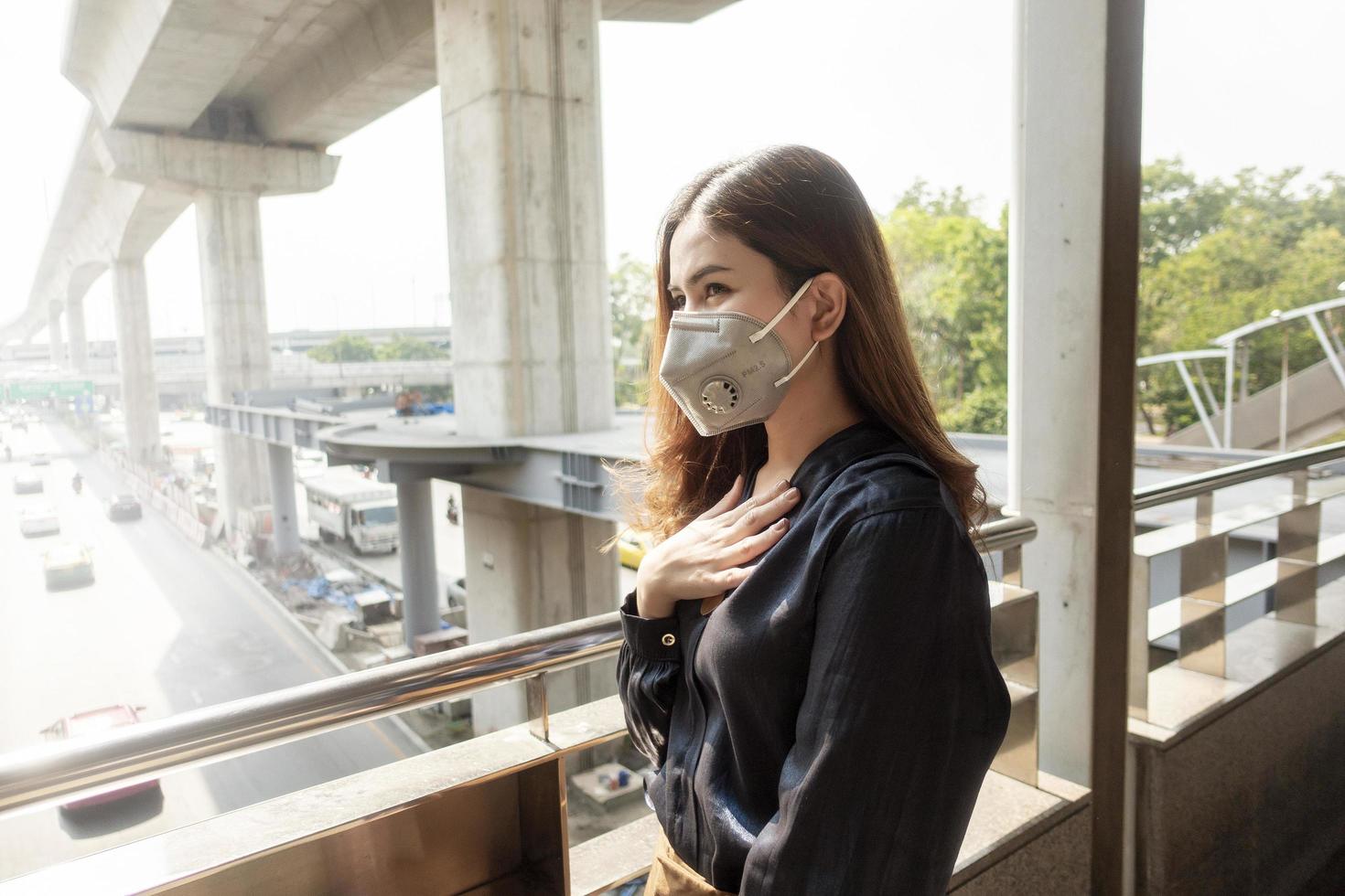 hermosa mujer con máscara antipolvo protege la contaminación del aire y pm 2.5 en la ciudad de la calle foto