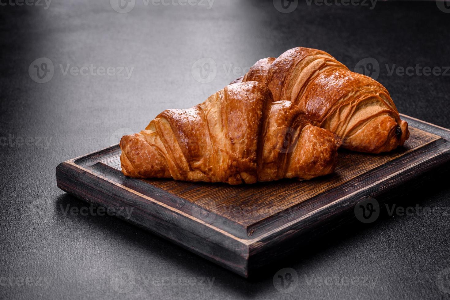 deliciosos croissants frescos y crujientes sobre un fondo de hormigón oscuro. sabroso desayuno foto