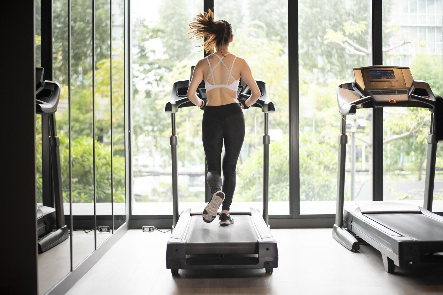 Beautiful asian sport woman is running on treadmill in the gym photo