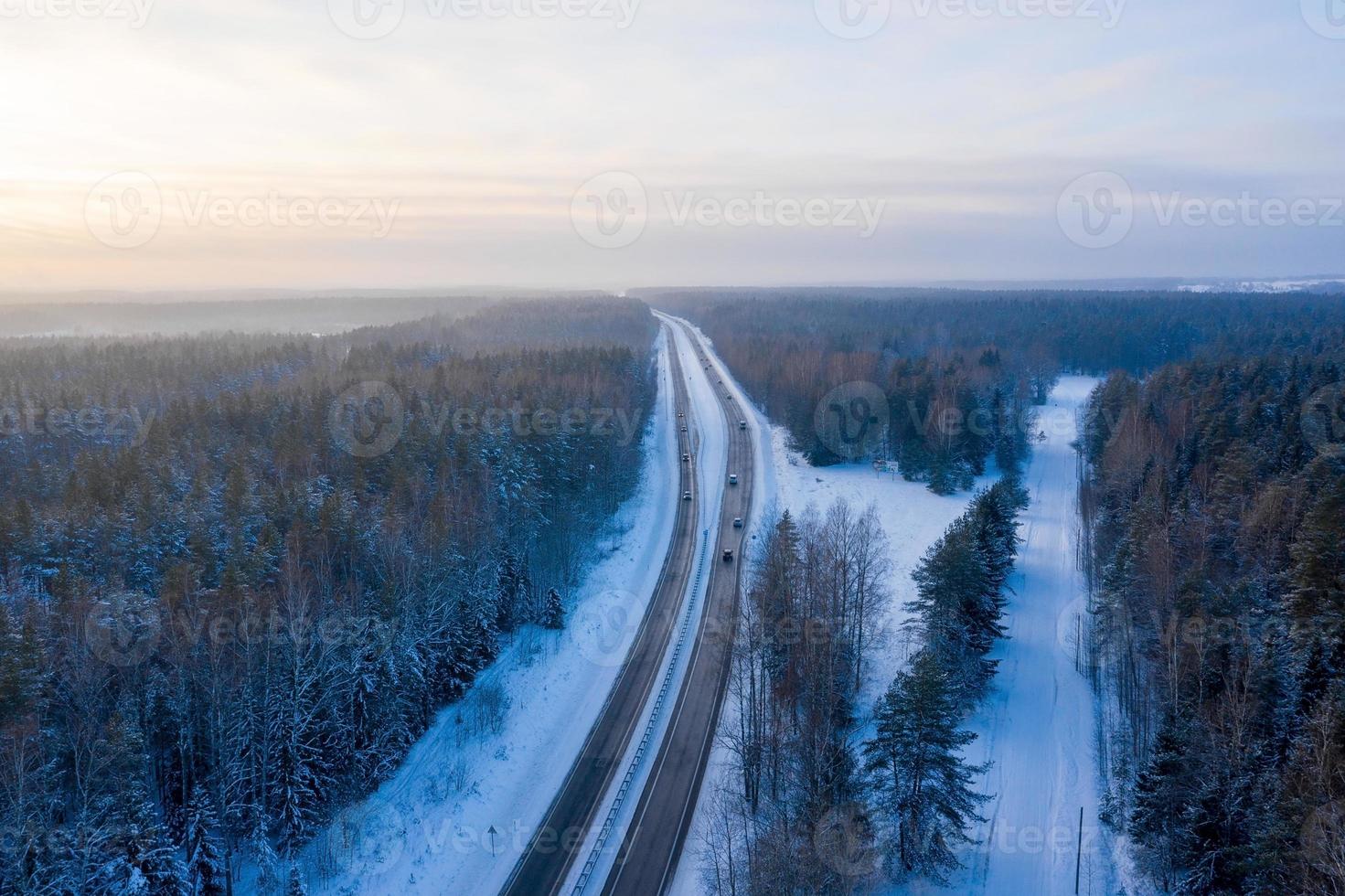 vista aérea de la carretera y el bosque en invierno. paisaje natural de invierno desde el aire. bosque bajo la nieve en invierno. paisaje de drone foto