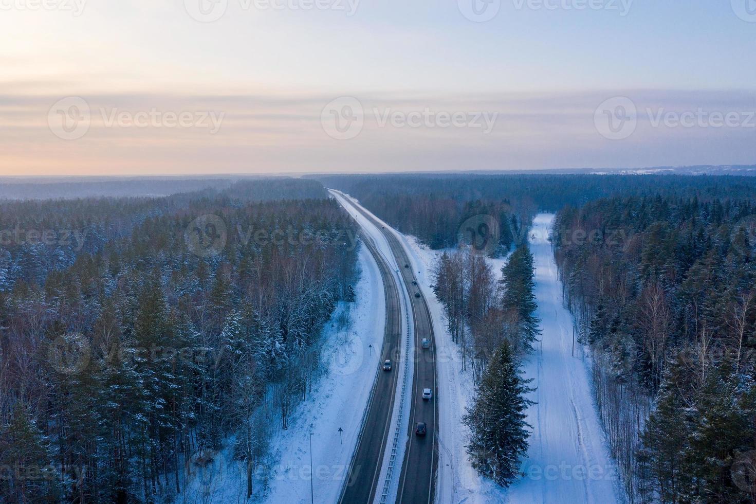 vista aérea de la carretera y el bosque en invierno. paisaje natural de invierno desde el aire. bosque bajo la nieve en invierno. paisaje de drone foto