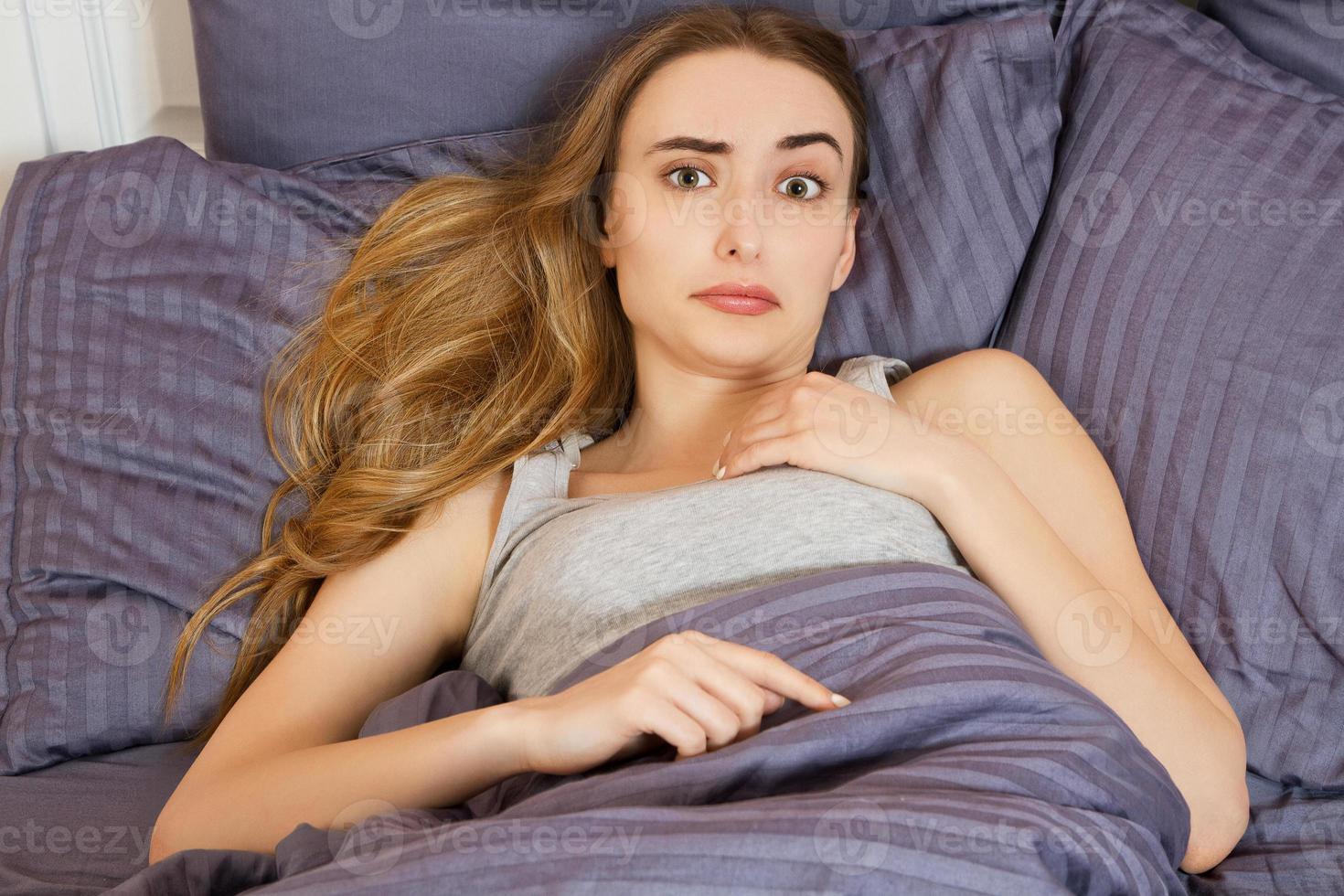 mujer que sufre de insomnio o indisposición en la cama en casa y mirando la cámara foto