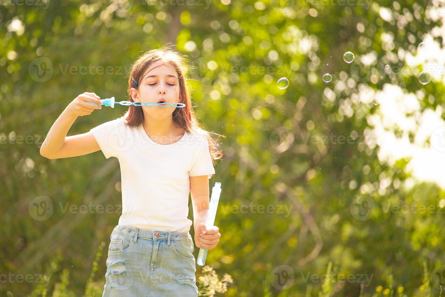 chica con una camiseta blanca. adolescente con pompas de jabón en la naturaleza. foto