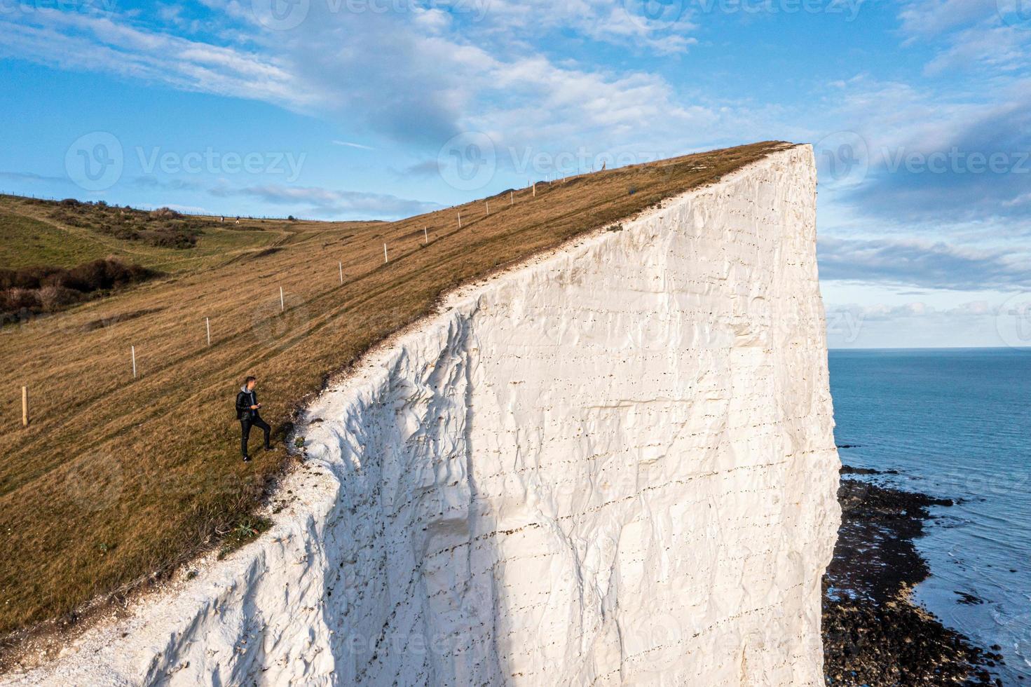 Young man standing on top of the White Cliffs of Dover. photo