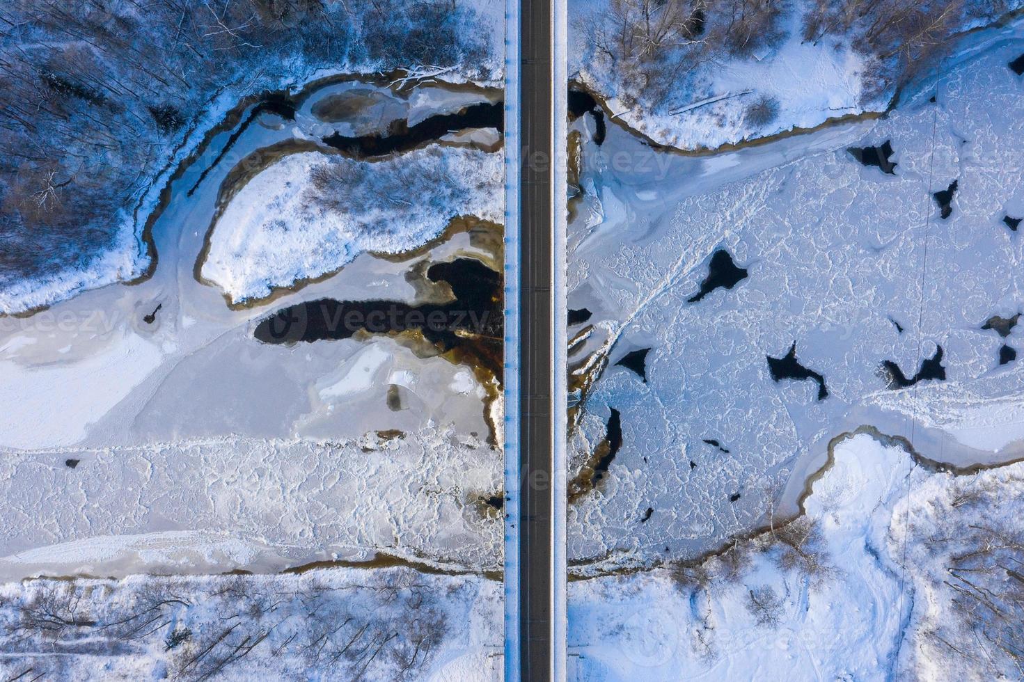 vista aérea de arriba hacia abajo de la temporada de invierno de un puente con una carretera en línea recta sobre el río foto