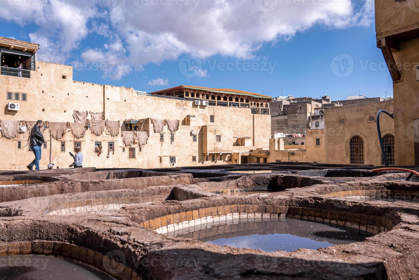 Tourist exploring next to brims of old stone water baths used for dyeing of leather photo