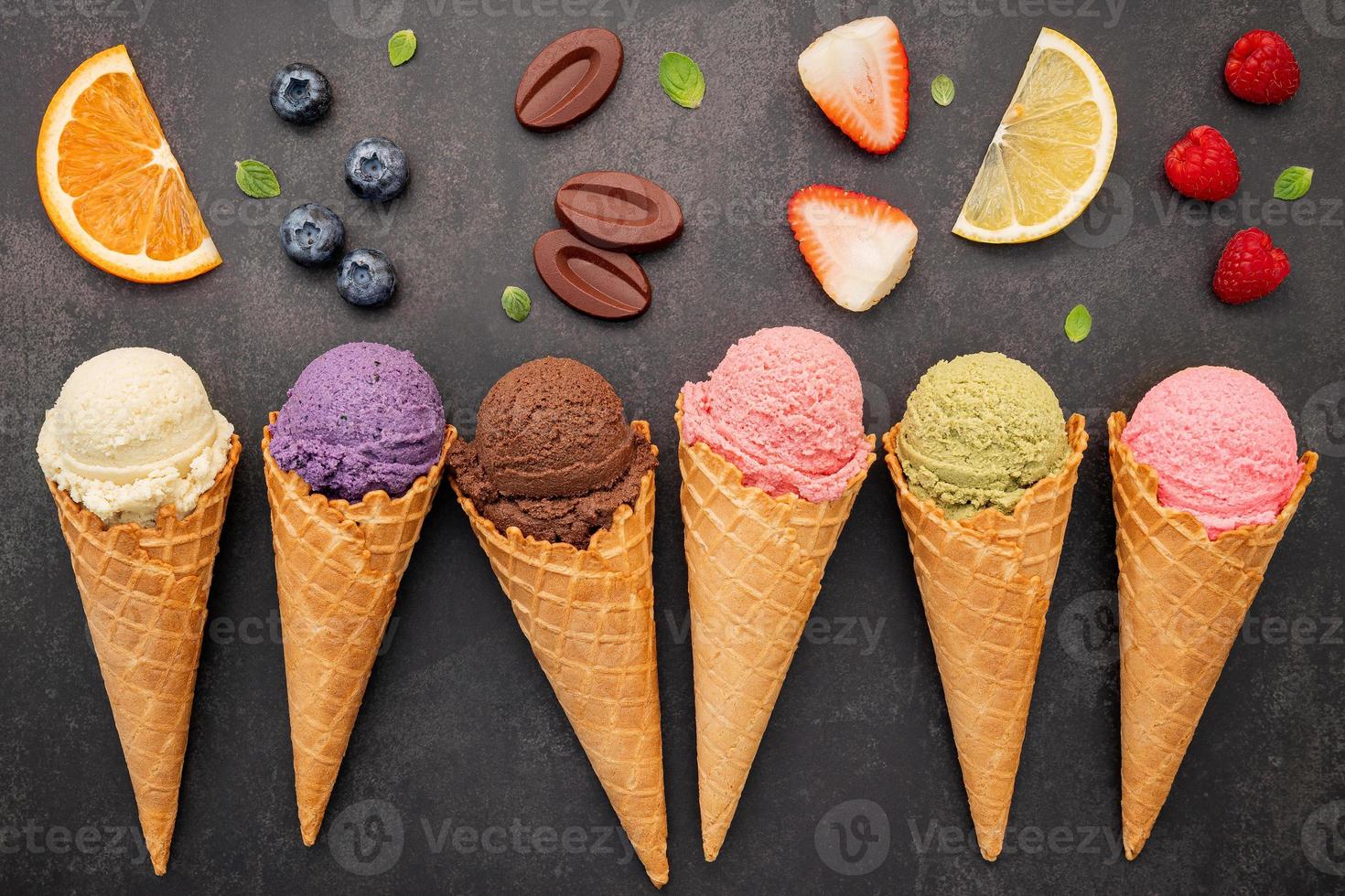 Colección de conos de helado planos laicos sobre fondo de piedra oscura. Cono de helado crujiente en blanco con espacio de copia para el diseño del menú de dulces. foto