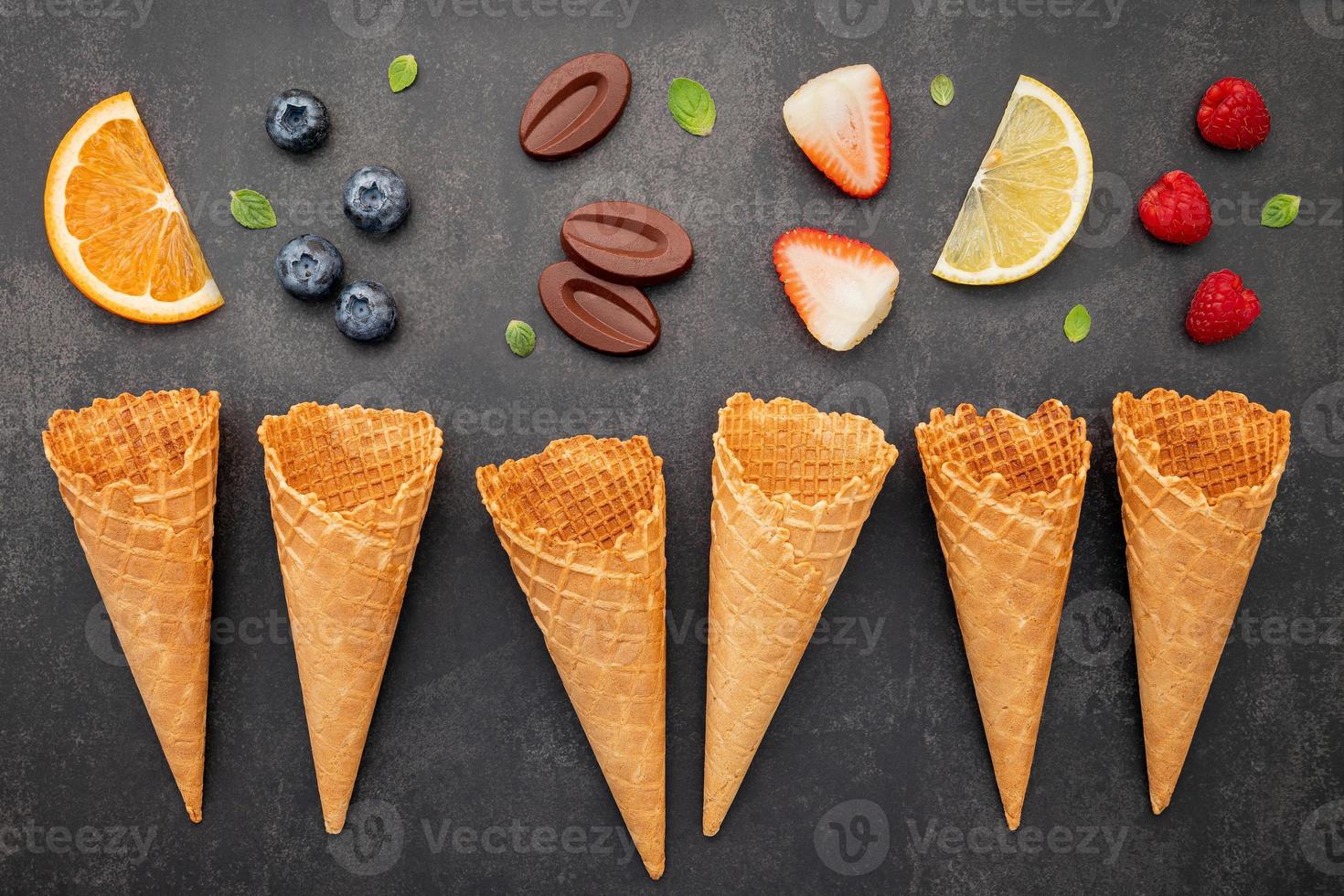 Colección de conos de helado planos laicos sobre fondo de piedra oscura. Cono de helado crujiente en blanco con espacio de copia para el diseño del menú de dulces. foto