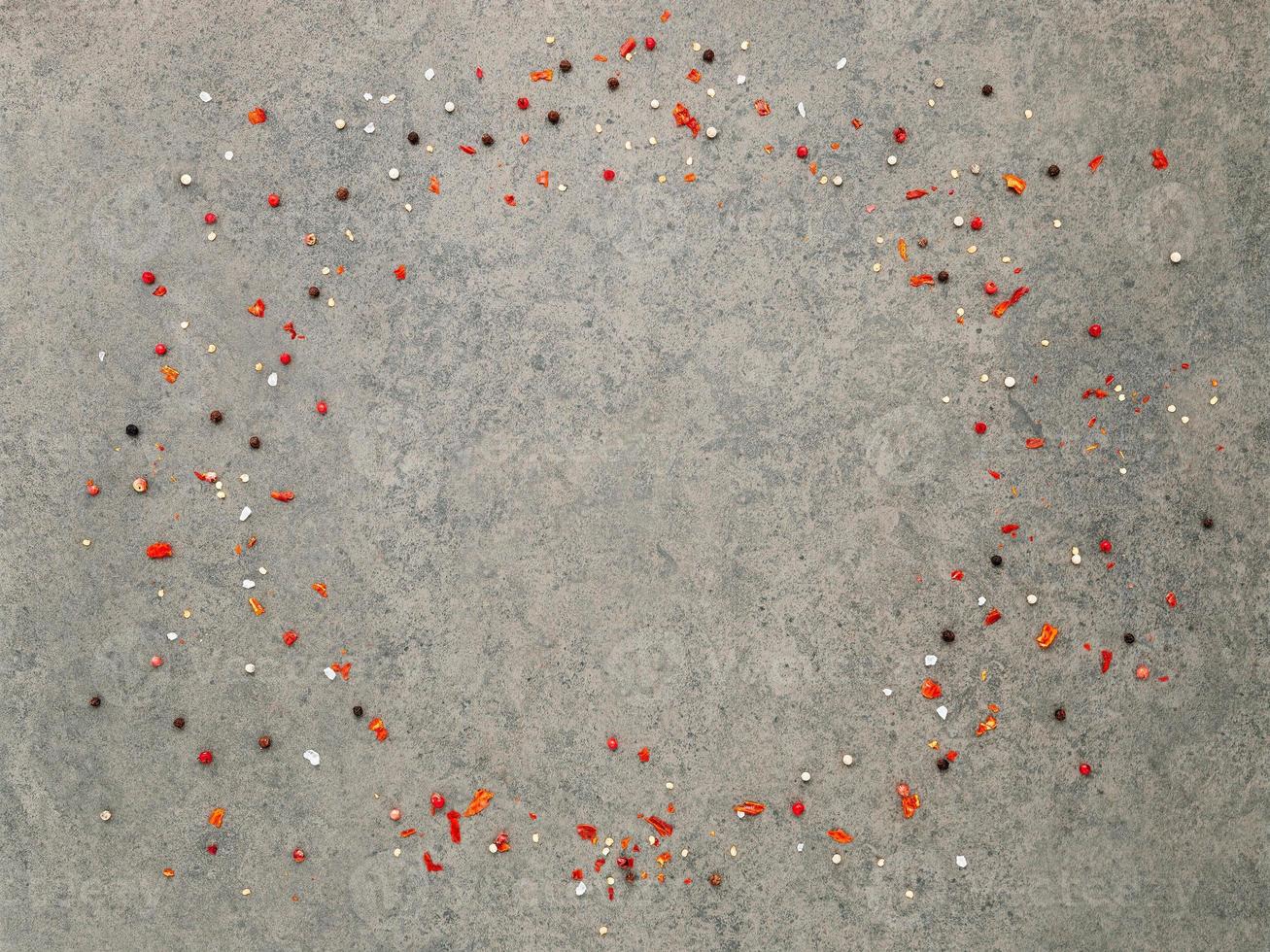 Top view of dark concrete background with peppercorn and chilli flakes. photo