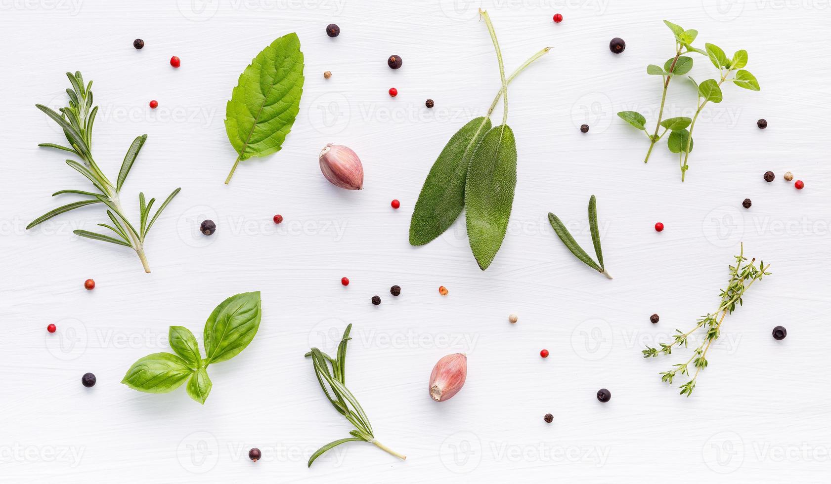 varios de especias y hierbas sobre fondo de madera. ingredientes planos de especias romero, tomillo, orégano, hojas de salvia y albahaca dulce en madera blanca. foto