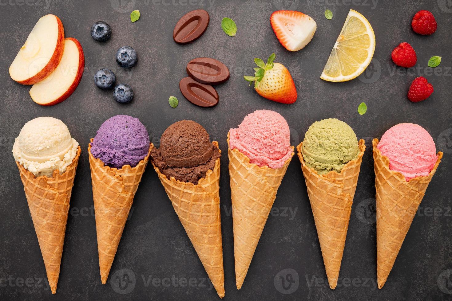 Colección de conos de helado planos laicos sobre fondo de piedra oscura. Cono de helado crujiente en blanco con espacio de copia para el diseño del menú de dulces. foto